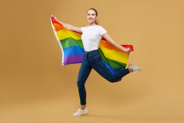 attractive blonde made a jump with a rainbow LGBT flag. photo shoot in the studio on a yellow...