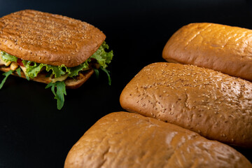 Fresh and tasty Italian panini, bread for sandwich with vegetables, sauce, salad, mushrooms, tomato and cucumber. Black background