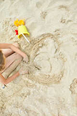 Top view of Little kid having fun on the beach and playing with sand toys