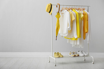 Rack with bright stylish clothes, shoes and accessories near light grey wall indoors, space for text