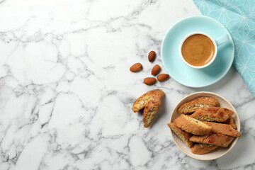 Flat lay composition with tasty cantucci and aromatic coffee on white marble table, space for text....