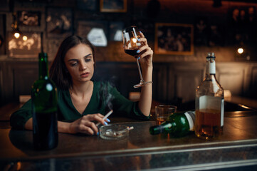 Unhappy woman drinks alcohol at the counter in bar