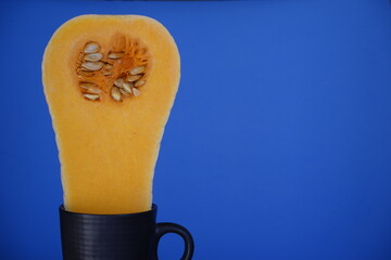 Primer plano de una calabaza de tipo cucurbita moschata cortada longitudinalmente, cuya parte...