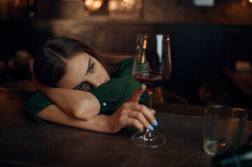 Depressed woman sitting in bar, full ashtray