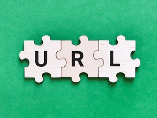 Text URL written on wooden jigsaw puzzle against green background.