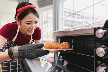 Young smiling asian female baking Croissant in oven, Bakery cooking concept