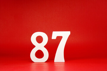 Eighty Seven ( 87 ) white number wooden Isolated Red Background with Copy Space - New promotion 87%...