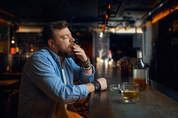 Stressed man drinks alcohol at the counter in bar