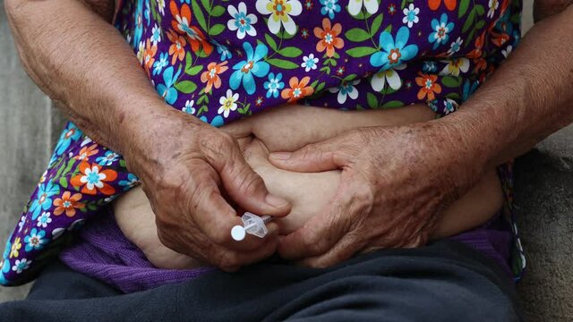 Close-up of a Senior woman giving herself an injection. Drug treatment, Congenital disease, Health care.