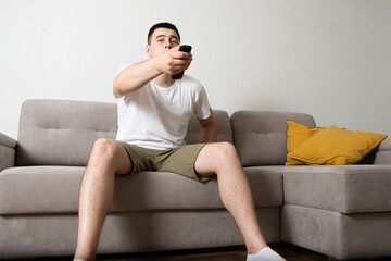 Man sitting on couch at home and watching TV