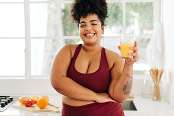 Body positive woman drinking fruit juice at home