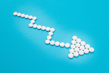 Global Pharmaceutical Industry and Medicinal Products - Downward Arrow Made from White Pills on Blue Background