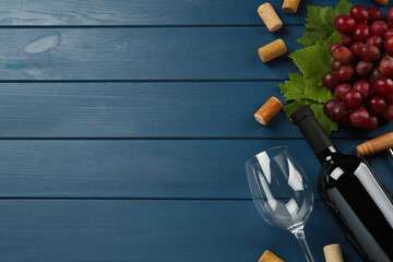 Tasty red wine and grapes on blue wooden table, flat lay. Space for text - obrazy, fototapety, plakaty