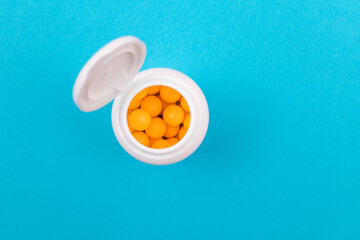 Global Pharmaceutical Industry and Medicinal Products - Yellow Vitamins or Pills in Bottle Lying on Blue Background. Copy Space, Top View, Flat Lay