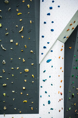 Artificial rock climbing wall showing various colored grips at outdoor gym adventure park.