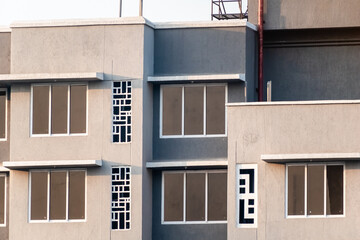 Windows of apartments in a grey modern concrete high rise building in suburban Mumbai.