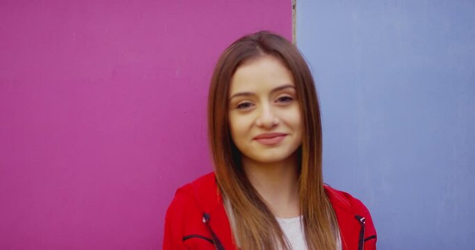 Portrait of Beautiful , pretty teen girl looking at camera and smiling in colorful background . Young and nice girl with natural beauty smiles and looks at camera . No makeup . Slow motion Close up  