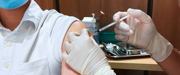 Asian man wear face mask receive Coronavirus vaccine injection jab by nurse or general practitioner...