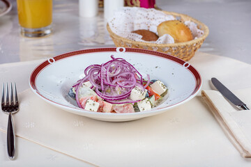 Lunch at the restaurant. On the table is a plate with a salad of cheese, olives and onions. Next to the juice, salt and pepper shaker.