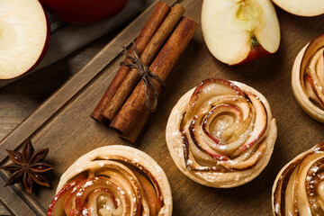 Freshly baked apple roses on wooden table, flat lay. Beautiful dessert
