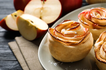 Freshly baked apple roses on dark wooden table, closeup. Beautiful dessert