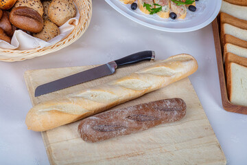 Wooden cutting board with black and white bread and a knife.