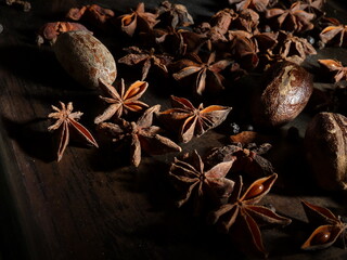 A cornucopia of star anise and nutmeg on a black background