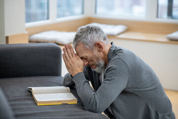 Fototapeta premium A gray-haired man sitting with eyes closed and saying the payers