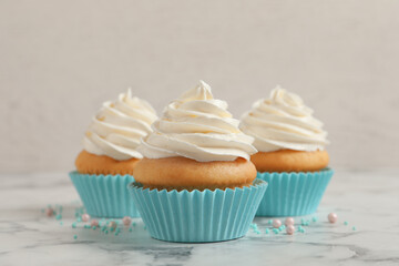 Delicious cupcakes decorated with cream on white marble table