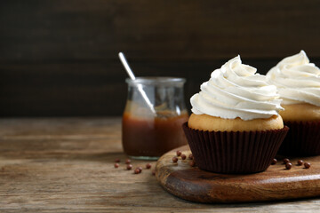 Delicious cupcakes with cream on wooden table. Space for text