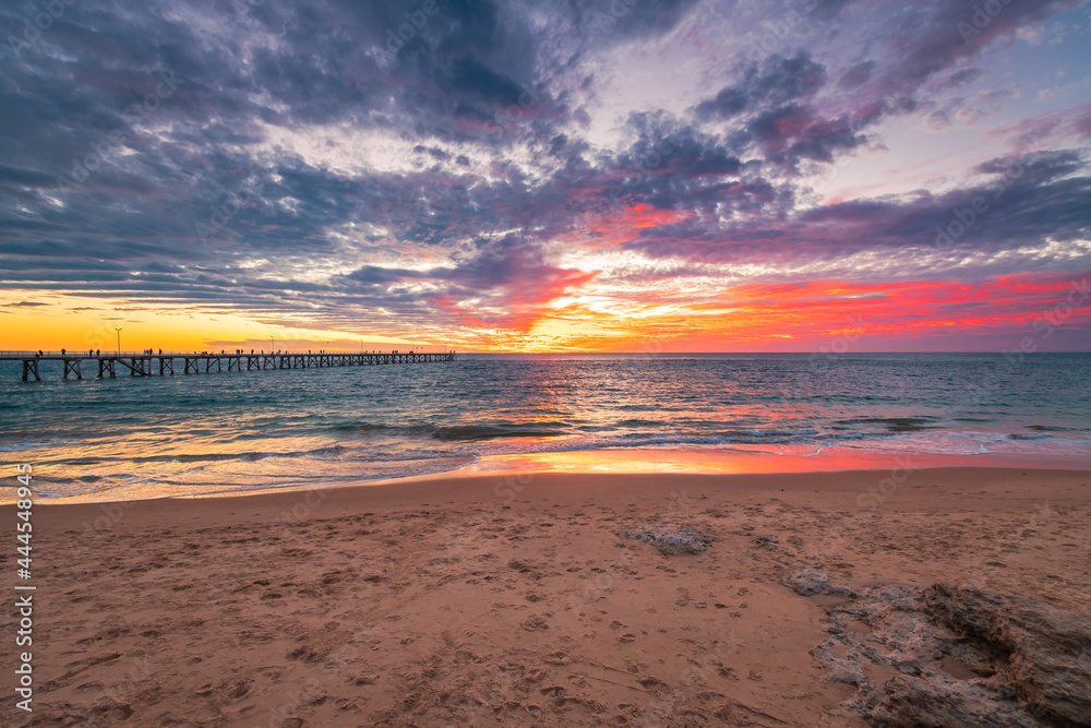 Wall mural port noarlunga beach foreshore with people on the pier and dramatic sunset in the background