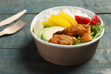 Healthy takeaway meal in paper container on blue wooden table