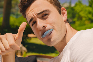 young teenager sticking out his blue tongue through the coloration of a candy and with a rocker...