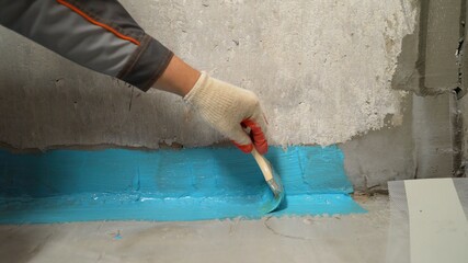 Close-up of a hand applying waterproofing in the bathroom. The process of applying waterproofing...