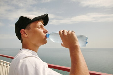guy in a cap drinks water from a bottle, summer, heat