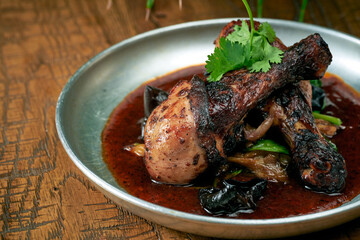 Grilled Chicken's leg with white barbecue sauce ponzu cucumbers and sauce in a plate on a wooden background