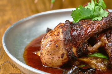 Grilled Chicken's leg with white barbecue sauce ponzu cucumbers and sauce in a plate on a wooden background