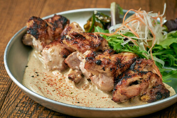 Grilled beef with white barbecue sauce ponzu cucumbers and sauce in a plate on a wooden background