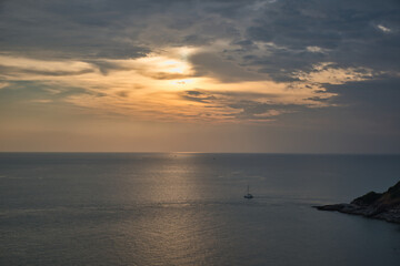 Beautiful, stunning panoramic view of the golden sky and reflections on the Andaman sea during the sunset at Promthep Cape landmark viewpoint in Phuket,
