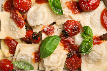 Tasty ravioli with tomato sauce and basil as background, top view