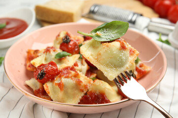 Tasty ravioli with tomato sauce served on table, closeup