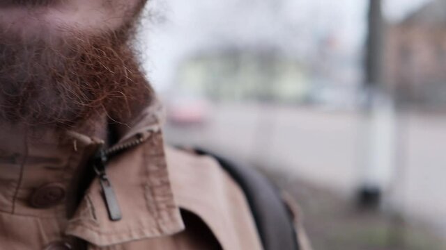 Close up view of bearded caucasian man smoking little cigar at winter day