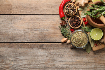 Flat lay composition with different natural spices and herbs on wooden table, space for text