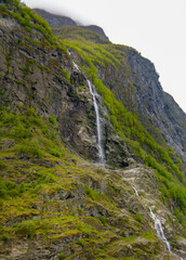 Fototapeta na wymiar Small scanty waterfall on the side of the mountain