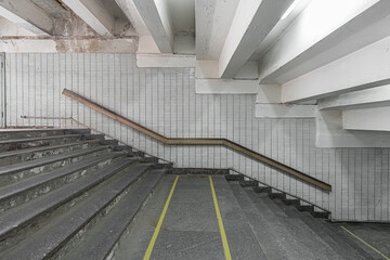 Stairs to the shabby underpass or subway station. Side view of empty stairs with a wall lined with ceramic glossy tiles.