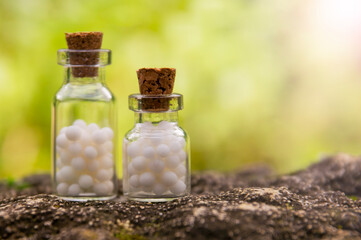 Homeopathic balls in bottles on the background of nature. Homeopathy alternative medicine concept.