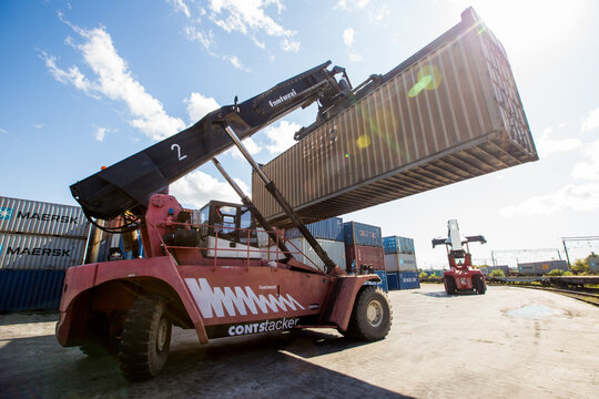 Summer, 2017 - Artem, Primorsky region - Logistic warehouse with containers in the open air. A reachstacker transports a large container through an open container terminal.