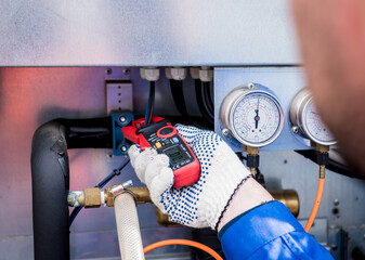 The technician checking power lines of the heat exchanger with current clamps