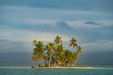 Tiny tropical, uninhabited island with coconut palm trees and white sand beach. Vacation and travel concept 