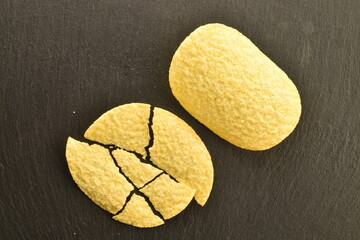 Several potato chips on a serving slate board, close-up, top view.